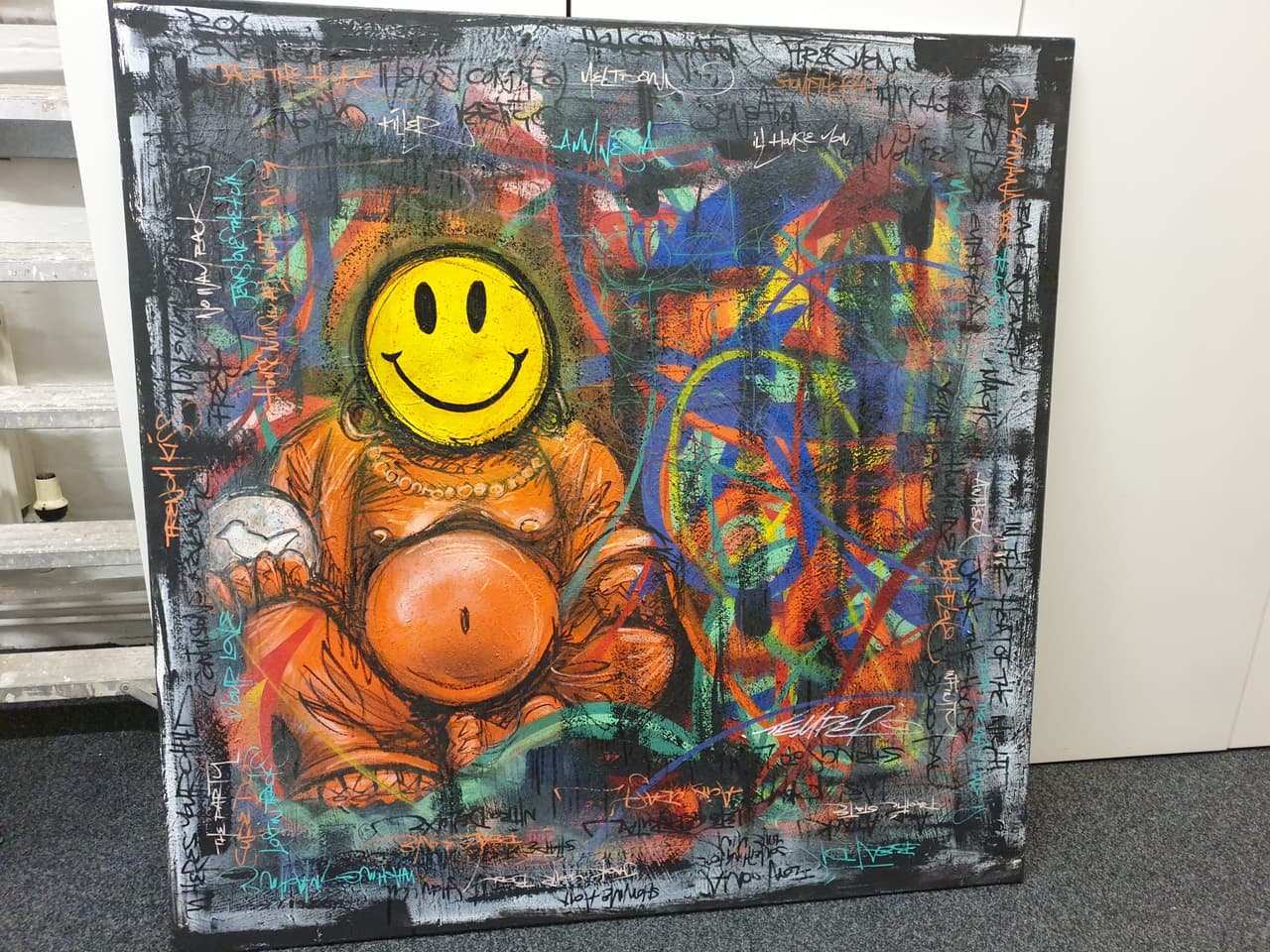 A colourful graffiti painting of a seated figure with a yellow smiley face