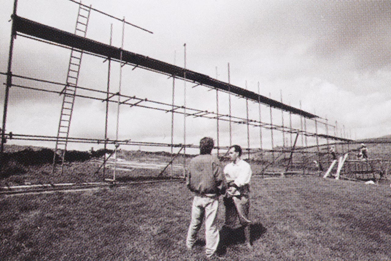 Archive photo, black and white: two men talking beside scaffolding in a field