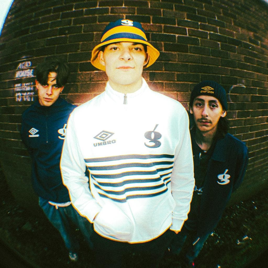 Three young men against a brick wall in giogoi and Umbro tops